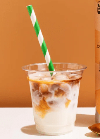 PUMPKIN SPICE SYRUP SEASON 4 a plastic tumbler filled with milk and topped with a pumpkin spice espresso shot and served with a straw